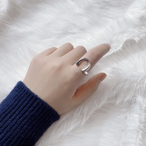 Detail of silver horseshoe U-shaped ring on hand with blue knit sleeve and plush background