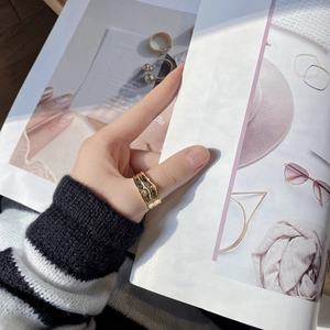 Gros plan d'une bague large dorée avec texture de lave portée par un mannequin