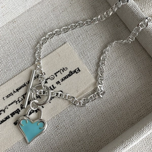 Detail of light blue heart enamel pendant with toggle clasp on silver anchor chain