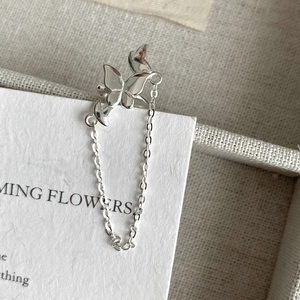 Macro shot of silver bow ear cuff with long tassel chain on an elegant jewelry display
