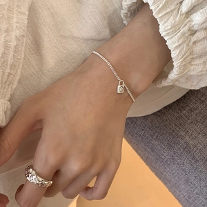 Close-up of S925 sterling silver chain bracelet with smiley lock and textured metal ring