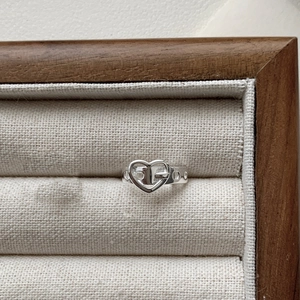 Close-up of S925 sterling silver heart buckle ring on a premium wood jewelry display