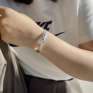 Detailed view of silver quilted pattern open bangle with classic textured design