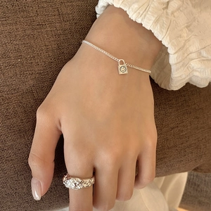 Close-up of S925 silver bracelet with smile padlock charm and textured band ring