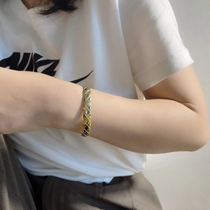 Macro shot of gold plated open bangle featuring classic quilted diamond texture design
