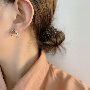 Close-up of crescent moon earring in S925 sterling silver worn on ear with high metallic luster