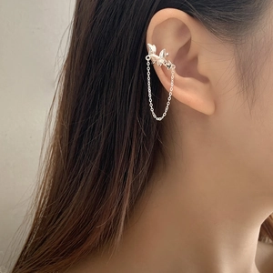 Detail of silver bow tassel ear cuff on ear without piercing for women