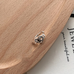 Close-up of S925 silver double heart crossover ring on light wood tray