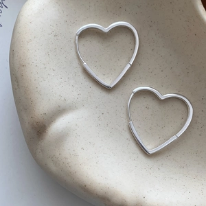 Boucles d'oreilles créoles cœur en argent sterling S925 sur un plat en céramique