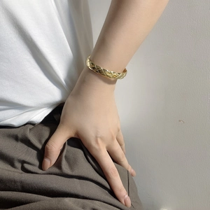 Close-up of golden quilted pattern open bangle on a model wrist for daily styling