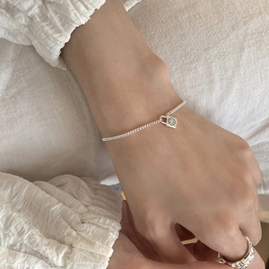 Close-up of a S925 sterling silver smile padlock bracelet and wavy textured open ring