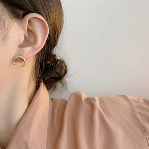 Detail of polished gold crescent moon stud earrings worn by a model in a punk chic style