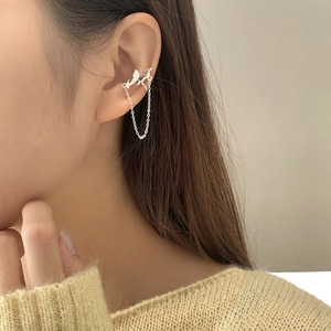 Detail of S925 silver bow tassel ear cuff on ear with shimmering metal chains