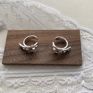 Detailed view of S925 sterling silver heart-shaped ear cuffs on a vintage wooden base