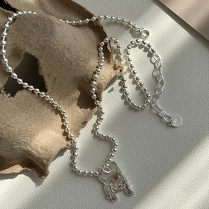 Détail d'un pendentif carlin en argent 925 et chaîne à billes avec fermoir mousqueton