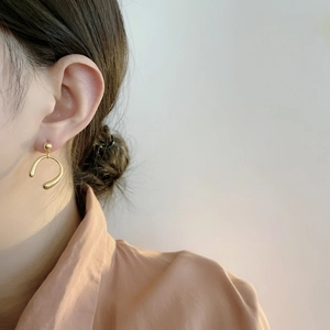 Vue latérale d'un mannequin portant d'élégantes boucles d'oreilles dorées en forme de U