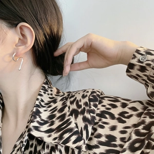 Close-up of wavy 925 sterling silver earrings worn by a model for a modern look