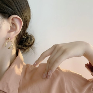 Détail de boucles d'oreilles dorées en forme de U au design fluide minimaliste