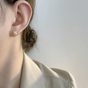 Detailansicht der unregelmäßigen goldenen Lava-Ohrstecker am Model für einen minimalistischen Stil