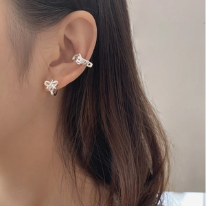 Detailed view of S925 silver bow stud earring and hollow cuff on a model's ear