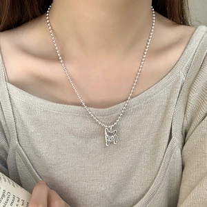 Détail d'un pendentif carlin en argent sur une chaîne à billes porté par un mannequin