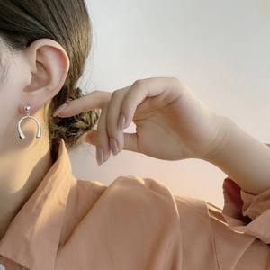 Détail macro d'une boucle d'oreille en U en argent sterling S925 sur un modèle féminin