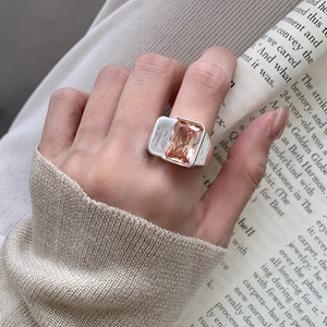 Detailed view of large rectangular amber zircon ring with engraved silver band on hand