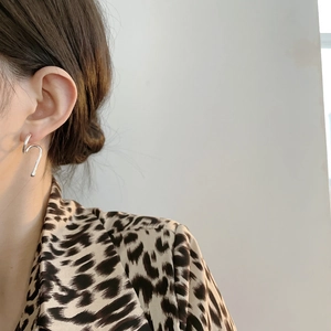 Close-up of minimalist 925 sterling silver earrings with abstract curved design on model