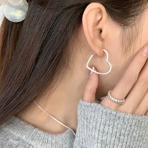 Gros plan de boucles d'oreilles cœur en argent 925 et bague torsadée sur un mannequin