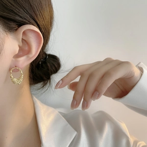 Minimalist gold oval earrings with textured finish shown on model in a side view