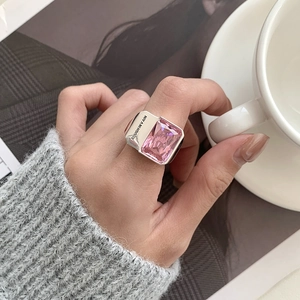 Chunky 925 silver ring featuring a large rectangular pink zircon on a hand with magazines