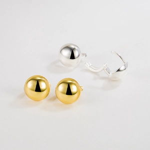 Detail view of gold and silver ball hoop earrings with secure click-top closure mechanisms