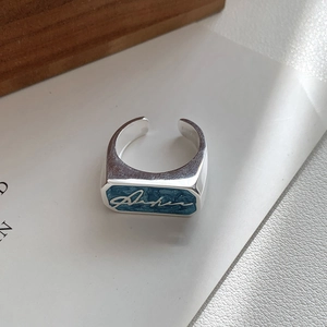 Detail of 925 silver ring featuring blue glitter enamel and signature design