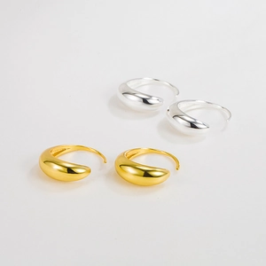 Primer plano de pendientes de gota minimalistas en acabados de oro y plata