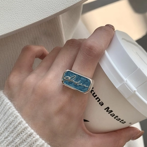 Macro view of wide silver ring with blue enamel rectangle and Aloha cursive script