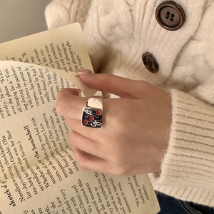 Vintage 925 sterling silver square ring with black enamel and red heart worn by a hand