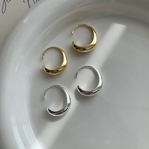 Vista de detalle de pendientes minimalistas de media luna en oro y plata sobre plato