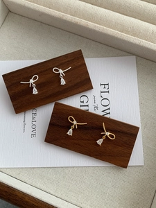 Detail of silver and gold knot bow earrings with teardrop zircon on jewelry display