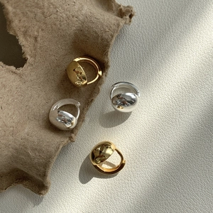 Detailed view of polished gold and silver hoop earrings on a textured backdrop