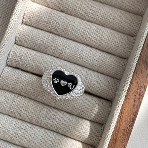 Macro detail of 925 silver heart ring with black enamel paw print and textured band