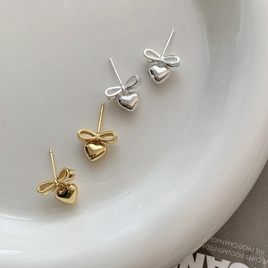 Detail of bow and heart pendant earrings showing S925 silver hallmarks and gold finish