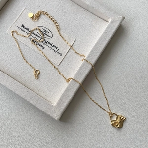 Gros plan du pendentif cœur doré avec un nœud 3D sur une chaîne de style minimaliste
