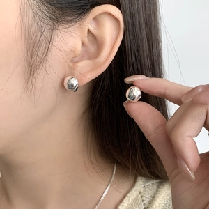 Close-up of minimalist 925 sterling silver ball stud earrings on a model ear
