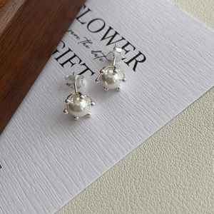 Detailed view of S925 sterling silver stamp and six-prong setting on pearl earrings