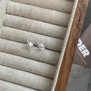 Close-up of S925 sterling silver star stud earrings on beige linen jewelry box display