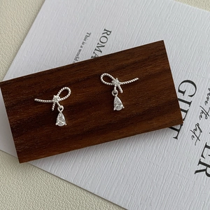 Detailed macro view of S925 sterling silver bow earrings with pear-cut crystal drops