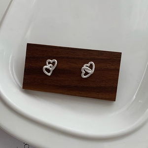 Macro view of S925 silver double heart stud earrings with hammered texture on wood
