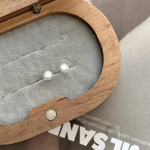 Macro detail of geometric S925 sterling silver stud earrings in a wooden jewelry box