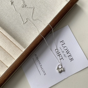 Collier en argent 925 avec pendentif cœur et nœud présenté sur un plateau à bijoux