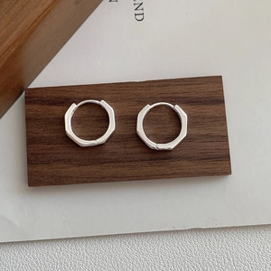 Gros plan de boucles d'oreilles octogonales géométriques en argent 925 sur bois